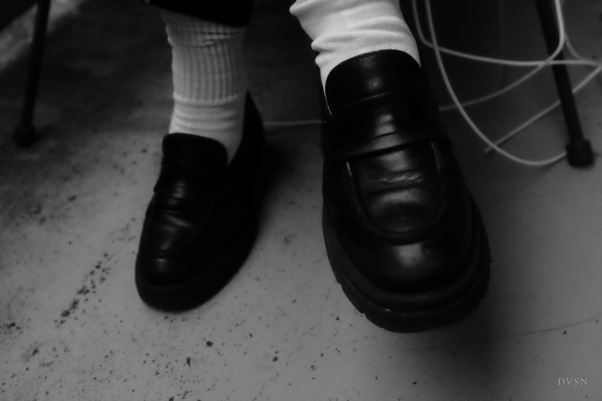 Black loafers and white socks on a concrete floor.