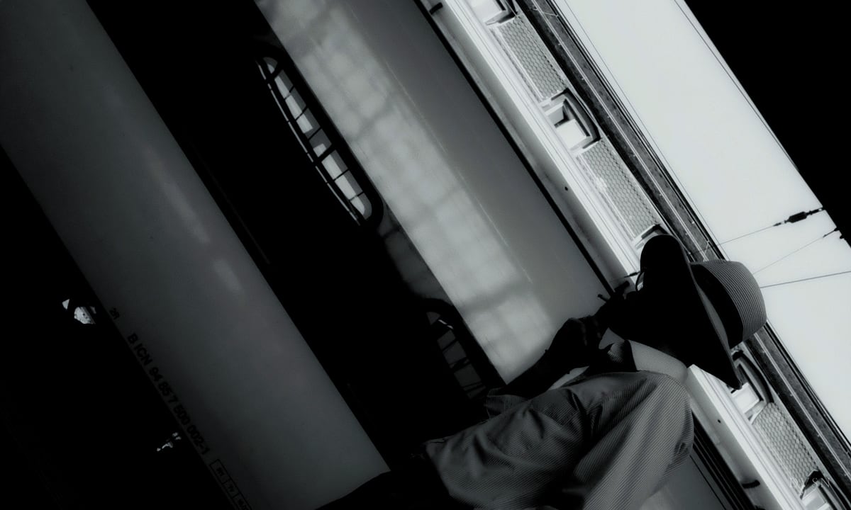 A man in a hat at a train window, framed on a steep diagonal.